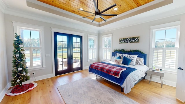 bedroom with crown molding, multiple windows, access to exterior, a tray ceiling, and french doors