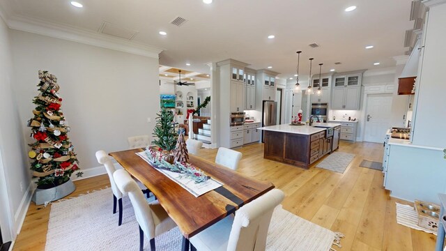 dining space featuring crown molding, sink, ceiling fan, and light hardwood / wood-style flooring