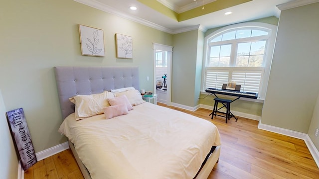 bedroom with ornamental molding, a raised ceiling, and light wood-type flooring