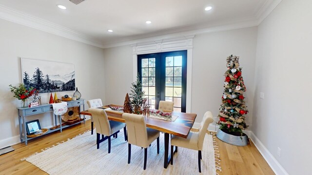 dining space with crown molding, light wood-type flooring, and french doors