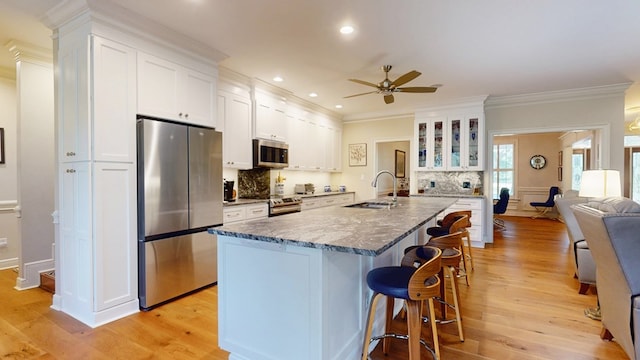 kitchen featuring stainless steel appliances, ceiling fan, a kitchen breakfast bar, light wood-type flooring, and ornamental molding