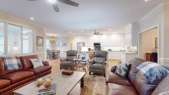 living room with a ceiling fan, light wood finished floors, ornamental molding, a chandelier, and recessed lighting