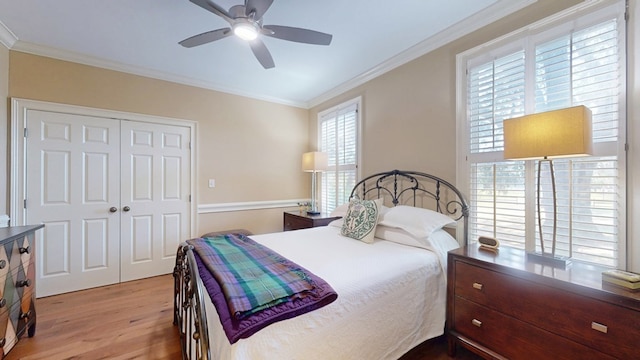 bedroom with ornamental molding, wood finished floors, multiple windows, a closet, and ceiling fan