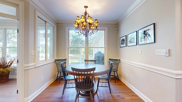 dining space with a chandelier, plenty of natural light, wood finished floors, and crown molding