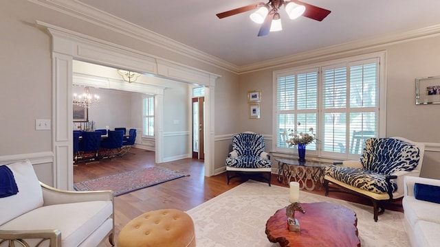 living room with wood finished floors, ceiling fan, crown molding, and a chandelier
