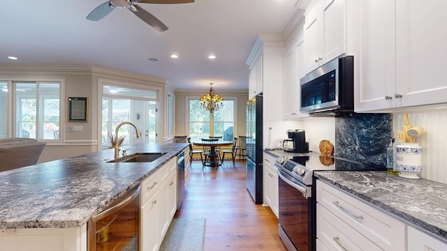 kitchen with stainless steel appliances, a sink, wine cooler, light wood-type flooring, and white cabinets