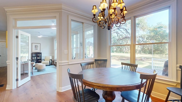 dining space with wood finished floors, a chandelier, crown molding, and a ceiling fan