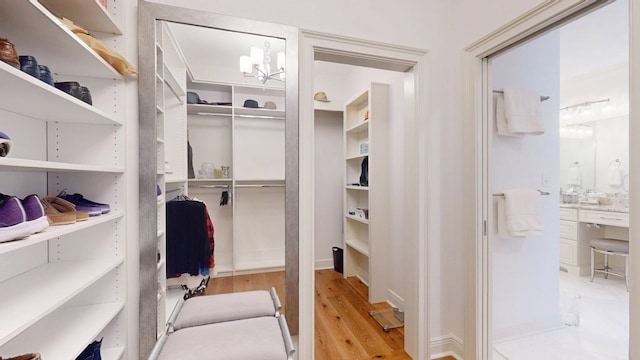 spacious closet with wood finished floors and a chandelier