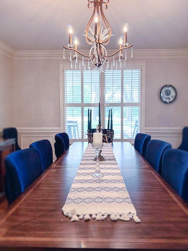 dining area featuring a chandelier, plenty of natural light, crown molding, a wainscoted wall, and a decorative wall