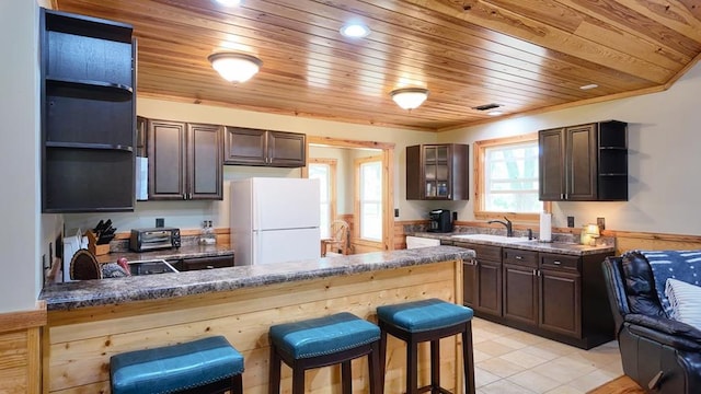 kitchen featuring open shelves, freestanding refrigerator, a peninsula, wooden ceiling, and dark brown cabinetry