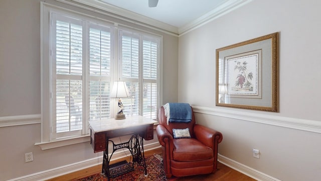 sitting room featuring healthy amount of natural light, wood finished floors, crown molding, and baseboards