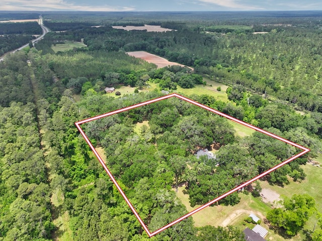 aerial view of property and surrounding area with a heavily wooded area and property boundaries highlighted