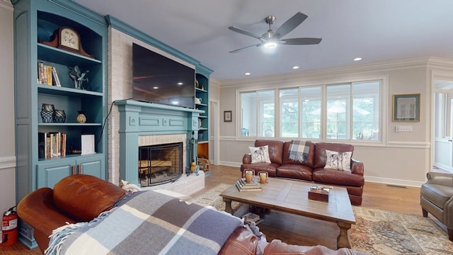 living room featuring a ceiling fan, ornamental molding, wood finished floors, a brick fireplace, and baseboards