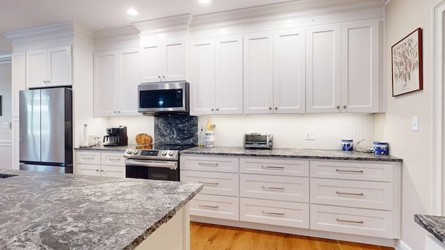 kitchen featuring appliances with stainless steel finishes, white cabinets, dark stone countertops, and recessed lighting