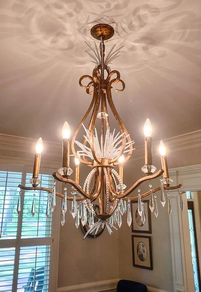 detailed view of crown molding, baseboards, and a chandelier