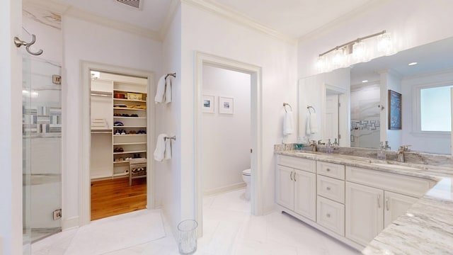 full bathroom with crown molding, a shower stall, double vanity, toilet, and a spacious closet