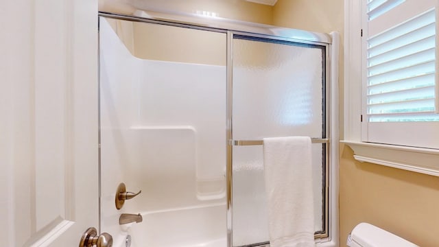 full bath featuring toilet and bath / shower combo with glass door