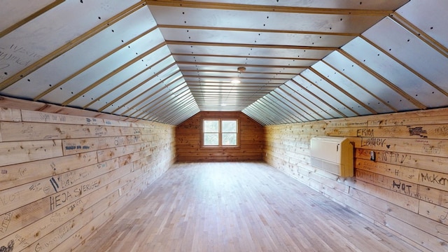 additional living space featuring wood walls, vaulted ceiling, and hardwood / wood-style flooring