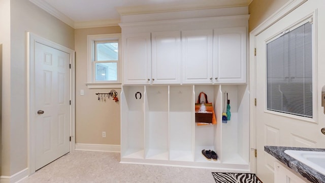 mudroom featuring baseboards, crown molding, a sink, and light tile patterned flooring