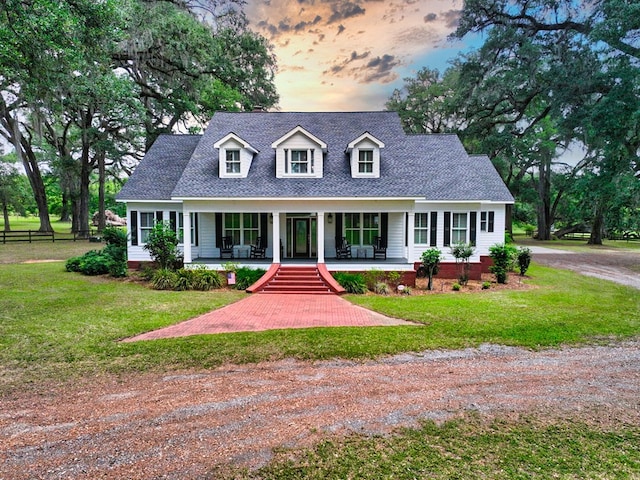 cape cod-style house with a porch, a shingled roof, and dirt driveway