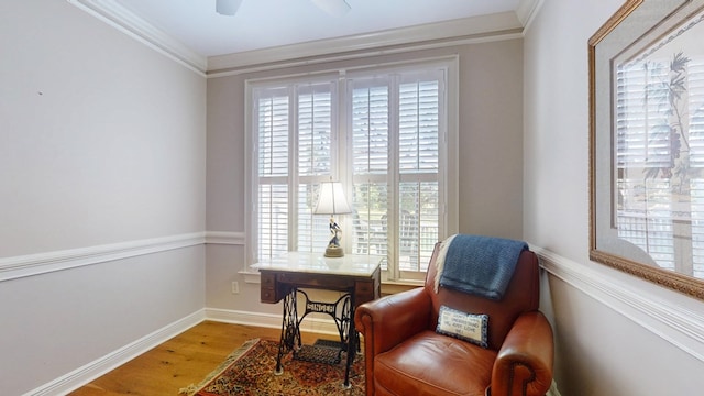 sitting room with wood finished floors, crown molding, and baseboards