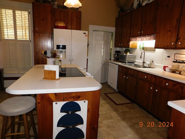 kitchen with sink, white appliances, a kitchen bar, and a kitchen island