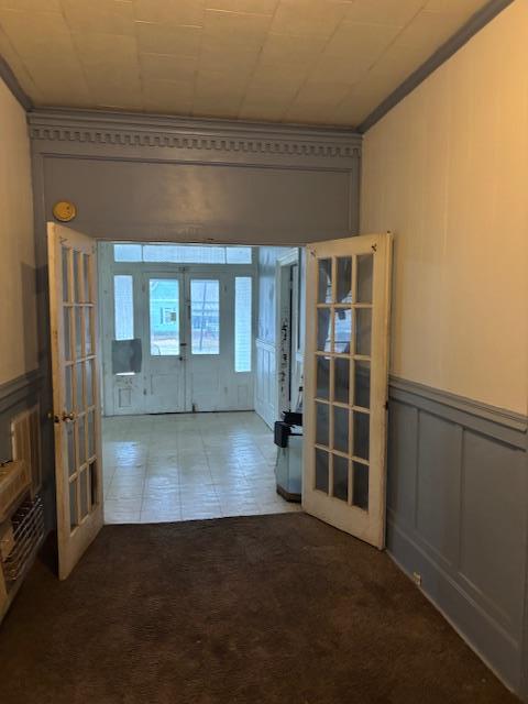 empty room with ornamental molding, carpet floors, and french doors