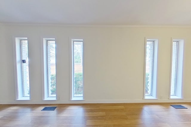 empty room featuring crown molding and light hardwood / wood-style flooring