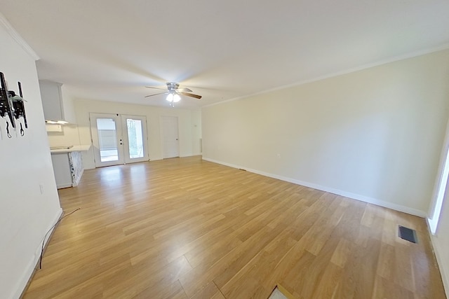 empty room with crown molding, ceiling fan, light hardwood / wood-style floors, and french doors