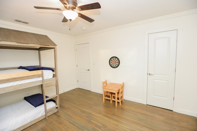 bedroom with baseboards, ceiling fan, visible vents, and wood finished floors