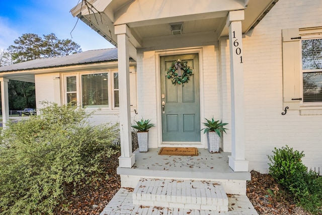 property entrance featuring brick siding and metal roof