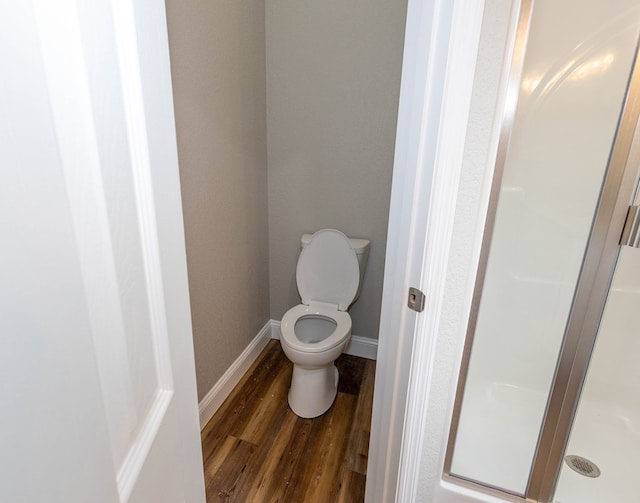 bathroom with hardwood / wood-style flooring, walk in shower, and toilet