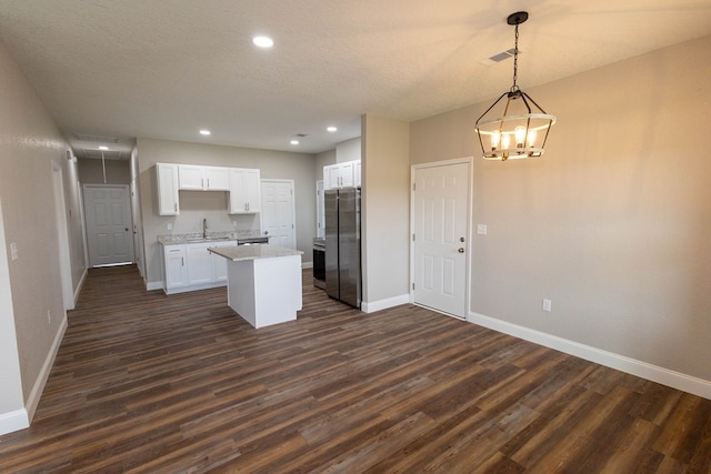 kitchen with stainless steel refrigerator, white cabinetry, hanging light fixtures, dark hardwood / wood-style floors, and a kitchen island