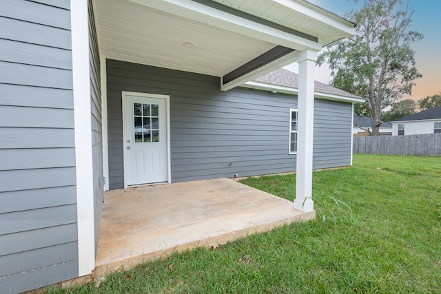 exterior entry at dusk with a patio area and a lawn