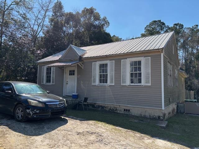 view of front facade with crawl space, metal roof, and a front yard