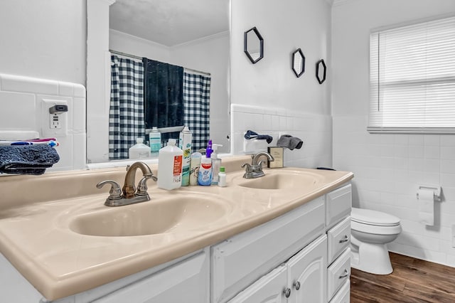 bathroom with toilet, crown molding, tile walls, vanity, and hardwood / wood-style flooring