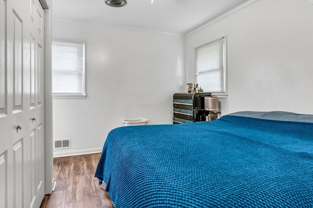 bedroom featuring crown molding, wood-type flooring, and multiple windows