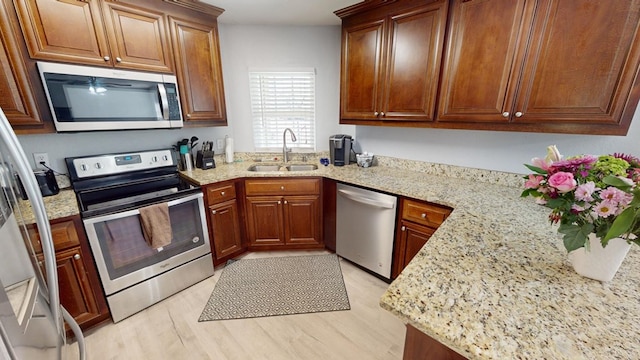 kitchen featuring stainless steel appliances, light stone countertops, sink, and light hardwood / wood-style flooring