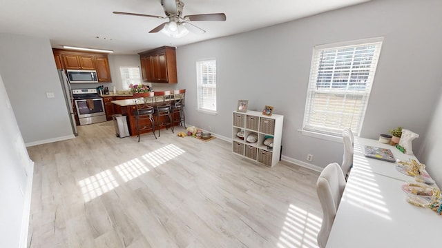 kitchen with a kitchen bar, a center island, ceiling fan, light hardwood / wood-style floors, and stainless steel appliances