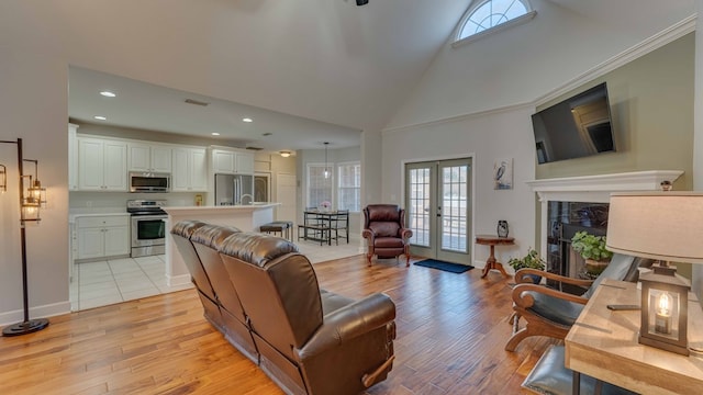 living room with high vaulted ceiling, light hardwood / wood-style floors, and french doors