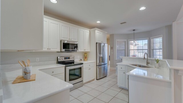 kitchen featuring sink, white cabinetry, hanging light fixtures, stainless steel appliances, and light tile patterned flooring