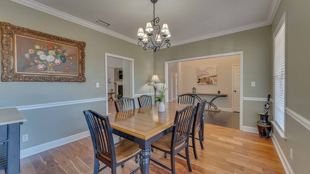 dining room featuring crown molding, a chandelier, and light wood-type flooring