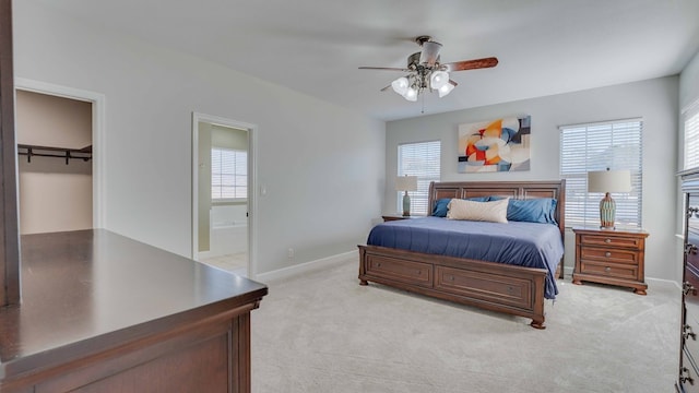 bedroom with ensuite bathroom, light colored carpet, and ceiling fan