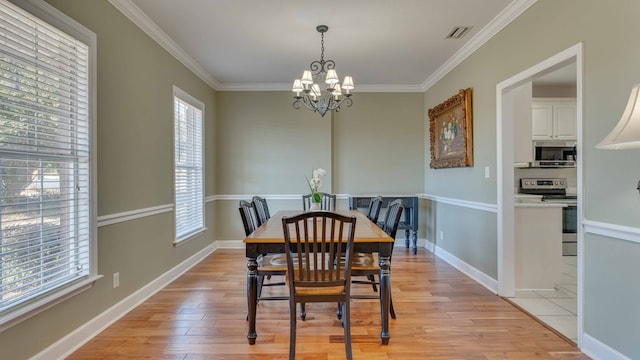 dining area with crown molding, an inviting chandelier, and light hardwood / wood-style flooring