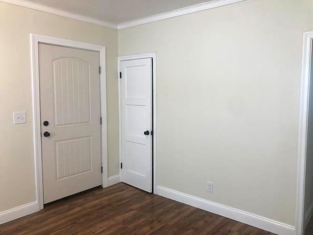 unfurnished bedroom with baseboards, ornamental molding, and dark wood-type flooring