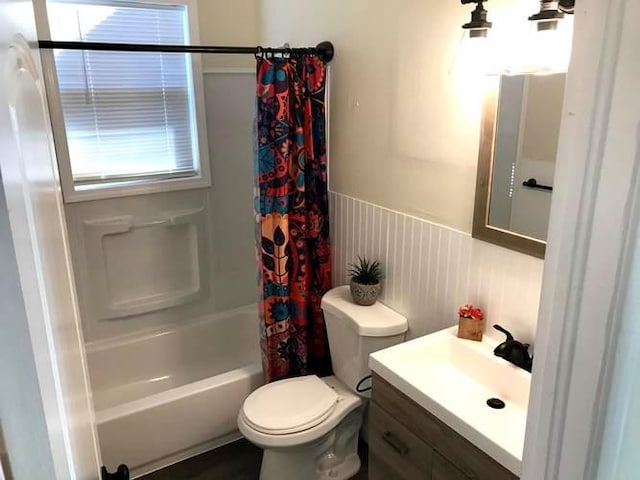 bathroom featuring a wainscoted wall, vanity, toilet, and shower / bath combo with shower curtain