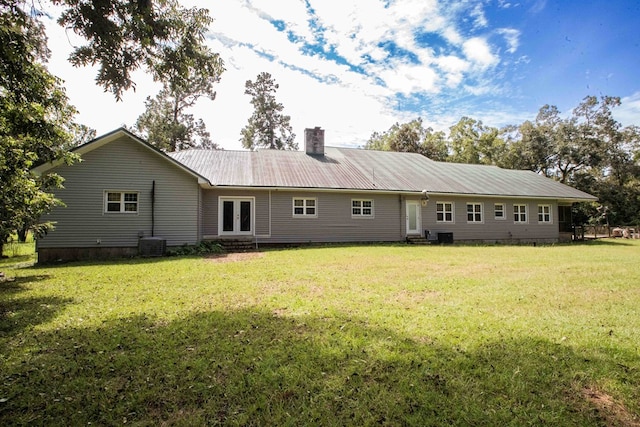 rear view of property featuring french doors, a lawn, entry steps, and metal roof