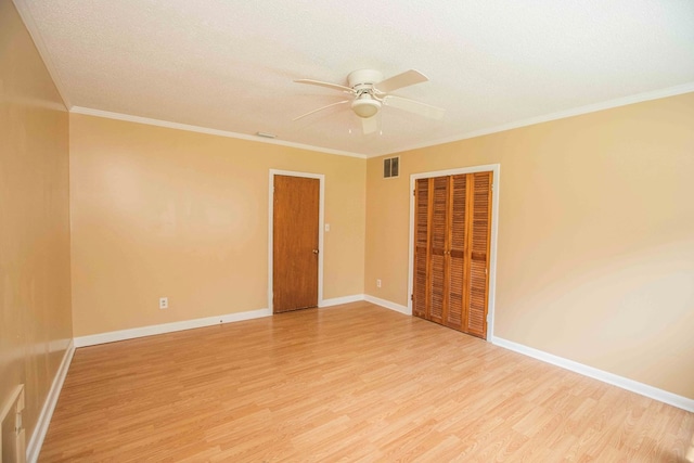 empty room with ornamental molding, baseboards, ceiling fan, light wood-style flooring, and visible vents