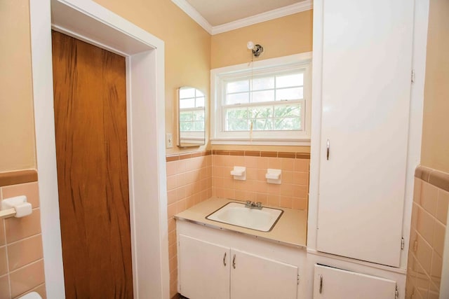 bathroom with tile walls, ornamental molding, vanity, and wainscoting