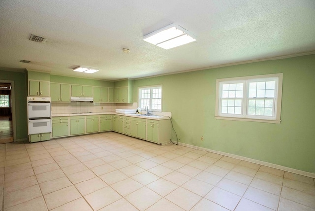 kitchen with green cabinetry, light countertops, white double oven, under cabinet range hood, and visible vents